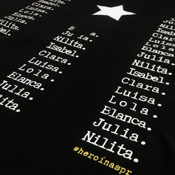 Detalles de la t-shirt negra de la bandera de Puerto Rico con los nombres de las #heroínaspr, siete mujeres históricas, latinas, puertorriqueñas y feministas. 